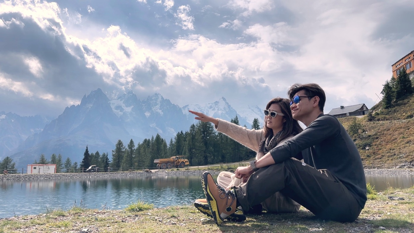 Two of us sitting by the lake, pointing at the peaks