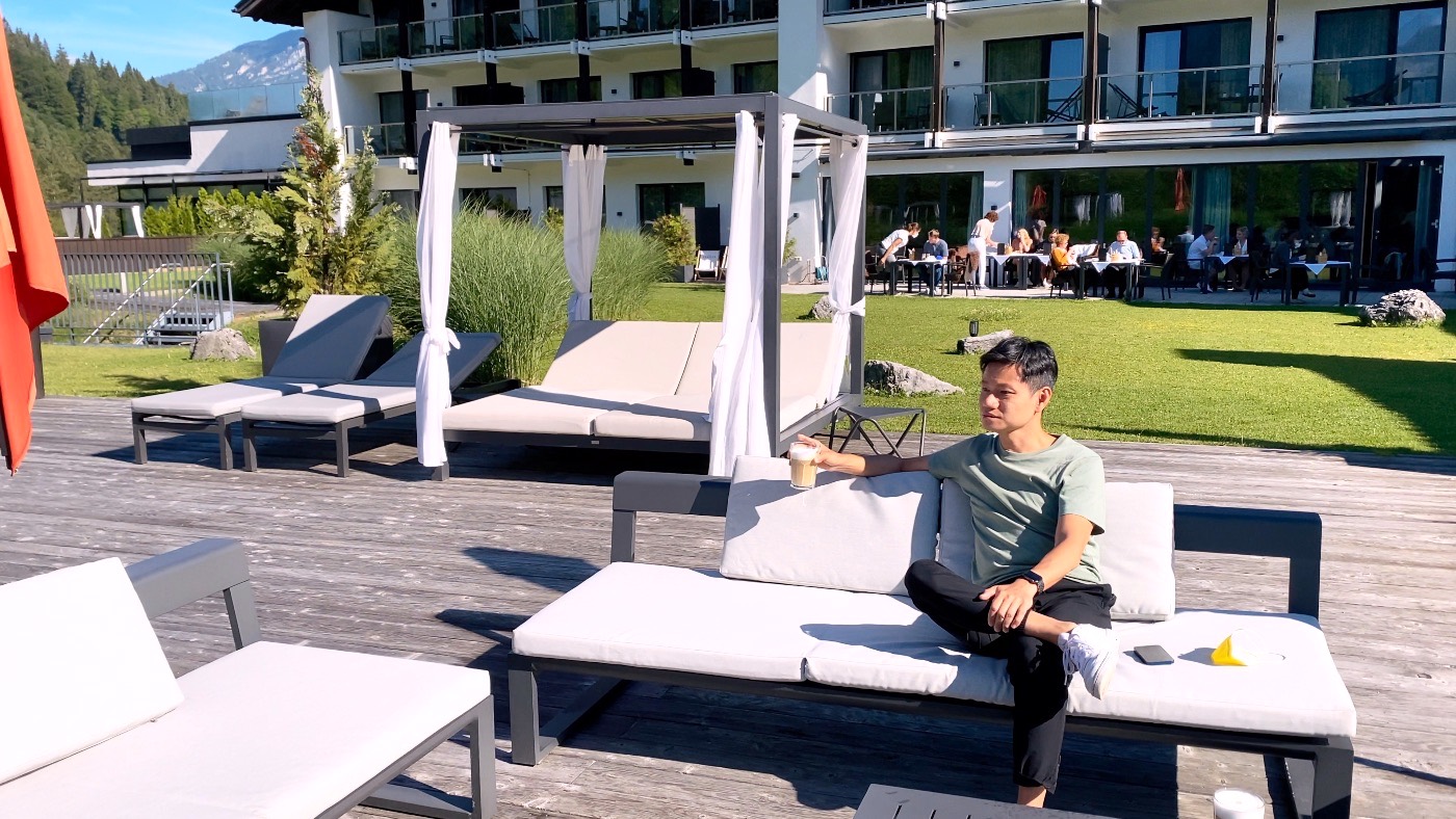 A man with a latte relaxing on a lounger on the hotel patio