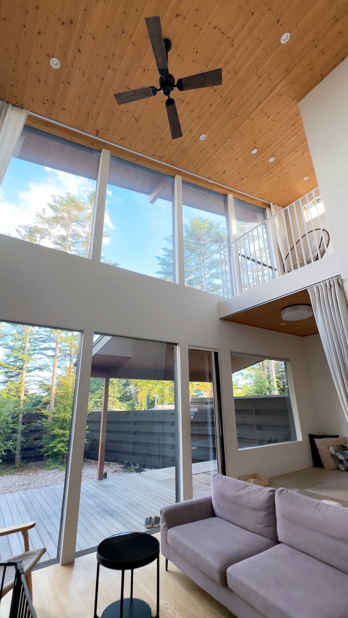 The villa interior — soaring timber ceiling, ceiling fan and floor-to-ceiling glass
