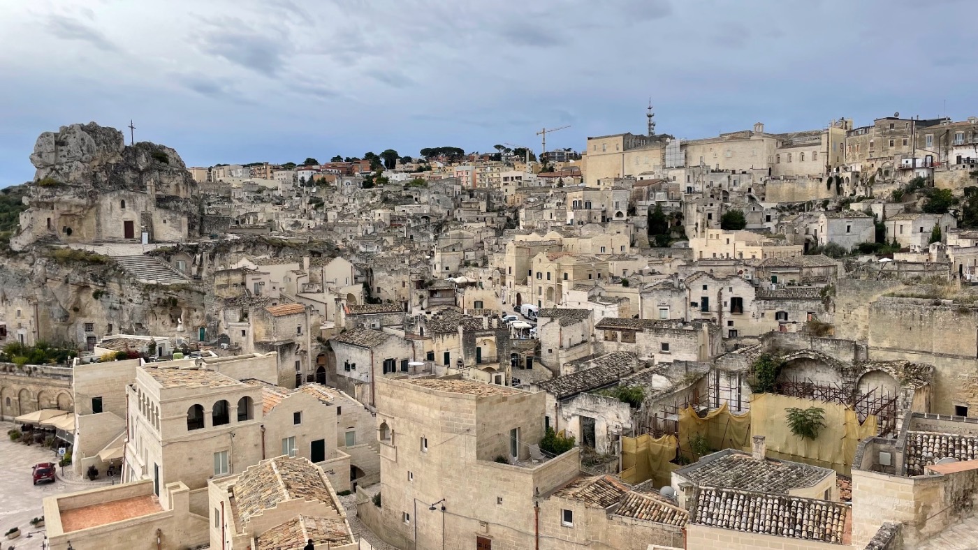 A wide panorama over the tightly-packed stone rooftops of the Sassi di Matera at dusk