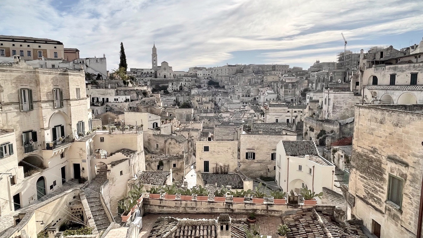 A wide view across the pale stone houses and church towers of the Sassi di Matera under a soft sky