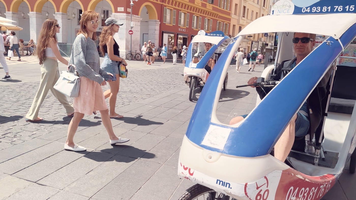 A street in the old town, busy with strollers and a little blue pedicab